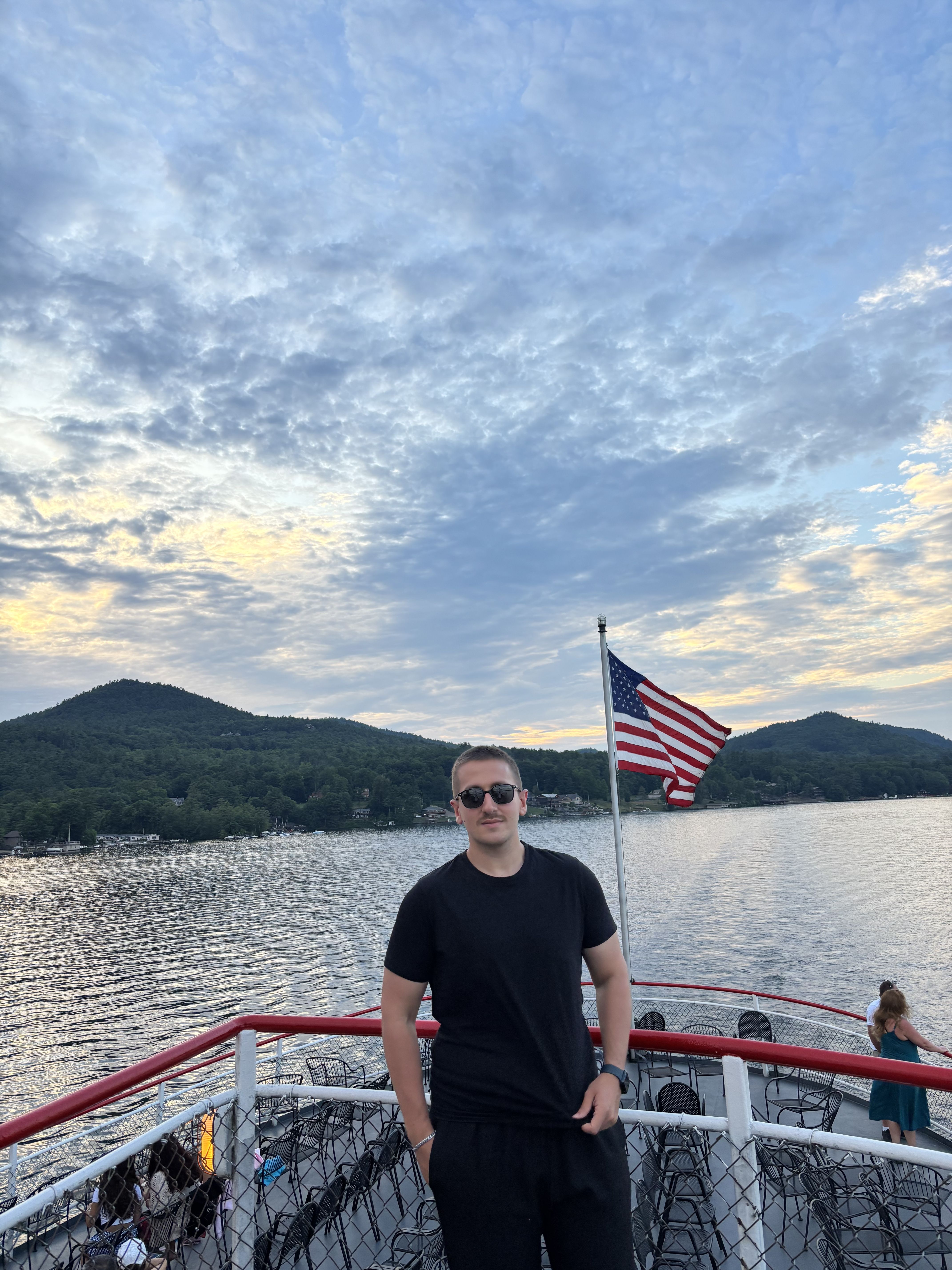 Onuralp Turgut beside an American flag on a lake in the United States