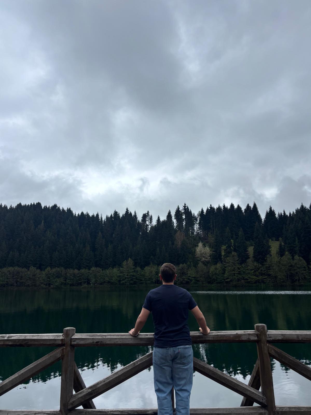 Onuralp Turgut looking across a quiet forest lake